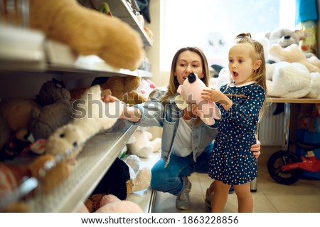 Mom and little girl choosing soft toys, kid's shop Royalty-Free Stock Photo #1863228856