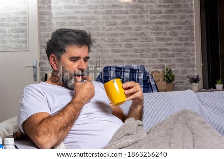Managing pain so he can get back to being productive. Shot of a mature man taking medication while standing at home during the day. Royalty-Free Stock Photo #1863256240
