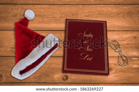Santa's hat, naughty and nice list and eyeglasses on wood table preparing for Christmas