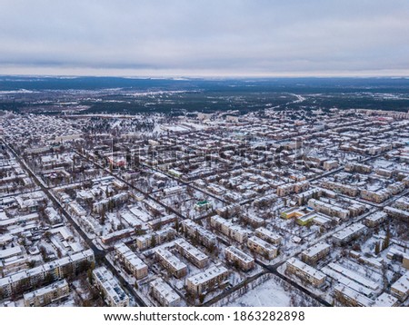 Aerial drone view of city roads and houses covered with snow. 