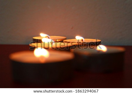 Many burning candles with shallow depth of field. Religious and devoutness scene: candles burning in the dark. Little child holding burning candle in darkness with noise and grain effect. 