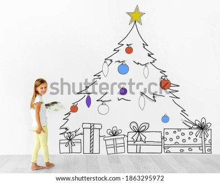 Little girl drawing christmas tree on wall