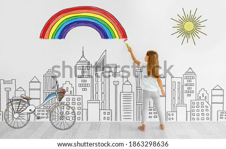 Little girl drawing rainbow on white wall