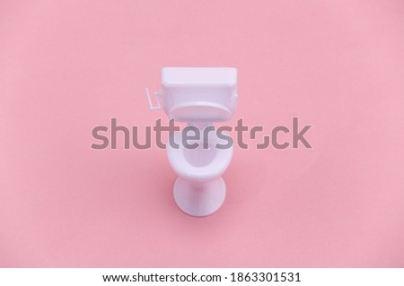 Mini white toilet on pink background. Minimalism. Top view