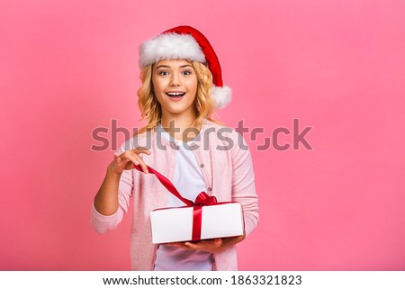 Excited funny kid child girl wears santa hat holding many gift box celebrating happy 2021 New Year isolated on pink background. Merry Christmas presents shopping sale.