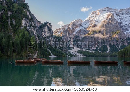 Autumn landscape of Lago di Braies Lake in italian Dolomites mountains in northern Italy. Drone aerial photo with Wooden boats and beautiful reflection in calm water at sunrise. Pragser Wildsee