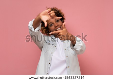 Happy mixed race woman framing photograph isolated on pink background. Creative photography concept.