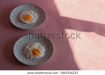 Homemade meal, Organic tasty cooked eggs for healthy breakfast on pink background, fancy ceramic plates, and flowers in a vintage artistic composition. Simple food composition.