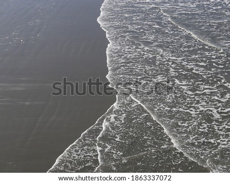 Waves flooding the shore black sand beach