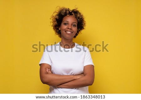 African american millennial woman looking at camera. Studio shot on yellow wall.