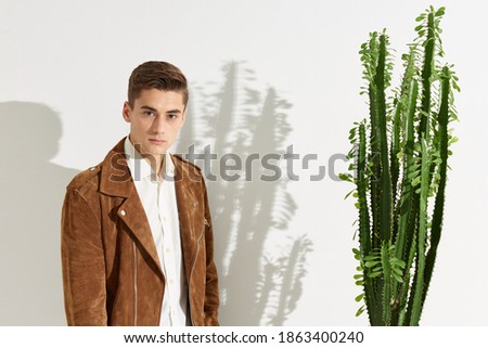 Portrait of a man in a brown jacket near a cactus flower