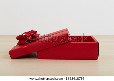 Red gift box with ribbon bow opened on vintage white wooden table Merry Christmas and Happy New Year