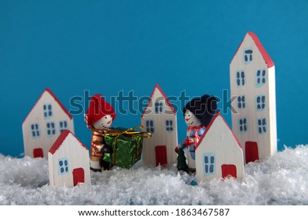Two snowmen with a gift walking snowcovered city close up. Christmas concept. Image contains copy space