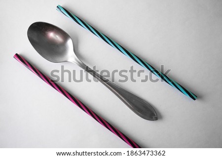 A spoon parallel to the colored straws between them