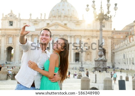 Tourists couple by Vatican city and St. Peter's Basilica church in Rome. Happy travel woman and man taking selfie photo picture on romantic honeymoon in Italy.