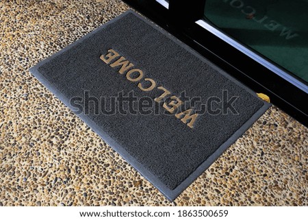 Welcome gray mat in front of door.