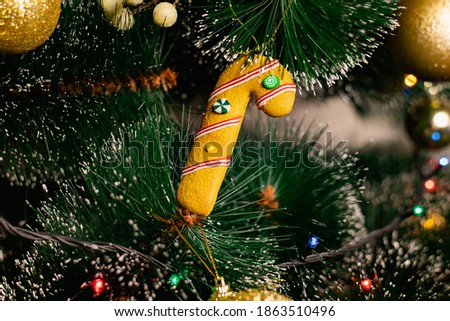 Golden Christmas decorations on a green artificial Christmas tree. Making a festive Christmas. Funny cute toys and gifts on the branches