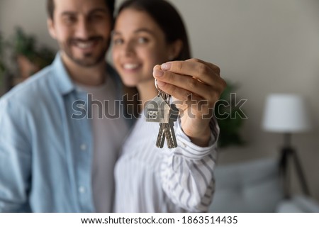 Crop close up of excited young Caucasian couple show keys to new shared home or dwelling. Happy man and woman spouses feel overjoyed moving relocating to own house. Rental, real estate concept. Royalty-Free Stock Photo #1863514435