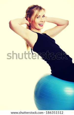 Young girl with big blue fit ball, isolated on white background