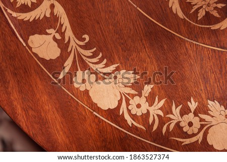 Decorative inlay carving on a wooden table, vintage furniture details Royalty-Free Stock Photo #1863527374