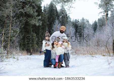 Happy family playing and laughing in winter outdoors in snow. City park winter day.
