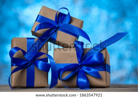 Christmas gift boxes with blue ribbons against blue lights garland and bokeh background. Holiday greeting card.