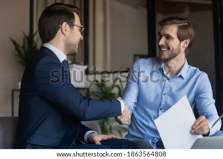 Good deal! Two business partners shaking hands after signing contract, client satisfied of getting loan insuring life handshaking with banker, happy job applicant appreciating hr for receiving place Royalty-Free Stock Photo #1863564808