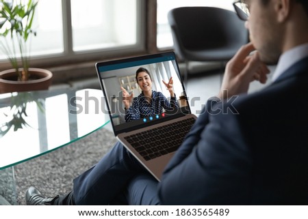 Thoughtful young male employee connecting with indian female colleague by video link using laptop, pensive businessman making conference call to mixed race woman consultant to get her recommendations Royalty-Free Stock Photo #1863565489