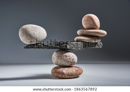 Balancing pyramid of sea pebbles on a gray background, the concept of harmony and balance, heavy and light. Stones in the form of scales with balancing stones.