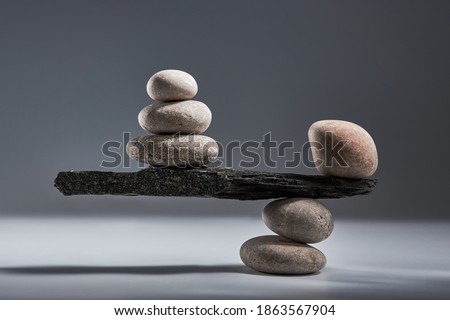 Balancing pyramid of sea pebbles on a gray background, the concept of harmony and balance, heavy and light. Stones in the form of scales with balancing stones. Royalty-Free Stock Photo #1863567904