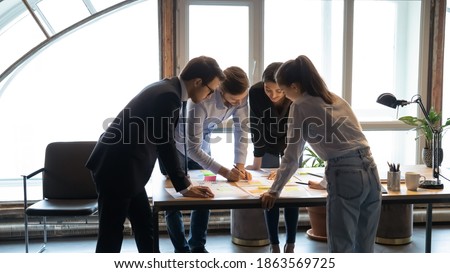 Experienced skilled male leader mentor demonstrating explaining international team of workers students interns principles of paperwork with statistic documents on marketing project scientific research Royalty-Free Stock Photo #1863569725
