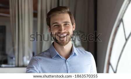 Profile picture of happy friendly young man corporate staff member posing for portrait in modern office space looking at camera with smile satisfied with self realization in job career opportunities