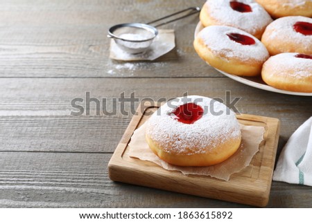 Hanukkah doughnut with jelly and sugar powder served on wooden table