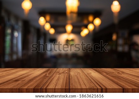 Empty wooden table top with blurred coffee shop or restaurant interior background. can be used product display. 