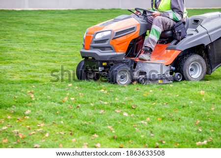 Professional lawn mower in motion, cutting the lawn. Cutting the grass in a park.