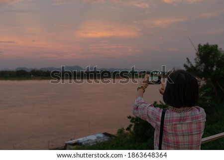 rear view of older woman using smartphone to shoot picture of mekong river during vacation