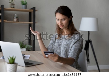 Confused young woman holding credit card in hands, stressed by financial payment mistake, blocked e-banking account or low quality money transfer service, feeling insecure shopping online at home. Royalty-Free Stock Photo #1863651157