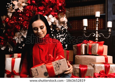 Full length photo of positive girl, hat hold big giftbox get on christmas night enjoy newyear tradition sit on floor carpet in house