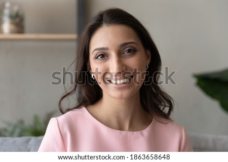 Head shot portrait social networks or dating application profile picture of attractive young happy indian arabic mixed race woman with toothy white teeth and perfect skin, looking at camera.