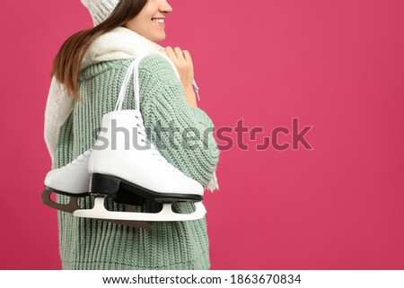Happy woman with ice skates on pink background, closeup. Space for text