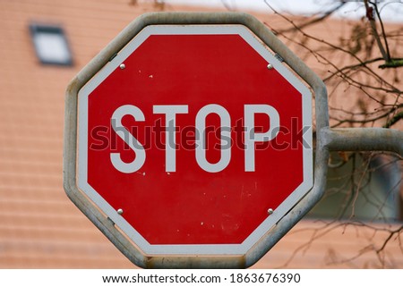 Traffic sign stop with roof in the background.