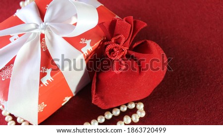 Red gift bag and Christmas gift box festively decorated with a white ribbon on a red background. Christmas background. Copy space