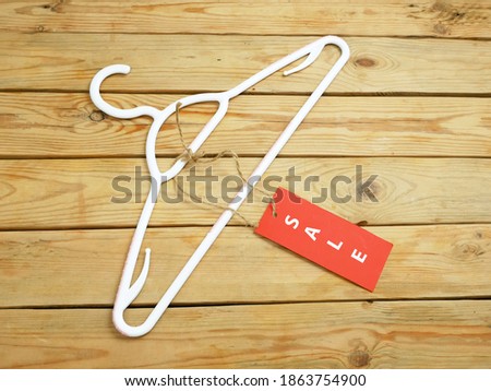 coat hanger and blank red price tag on wooden background, clothing sales concept, closeup