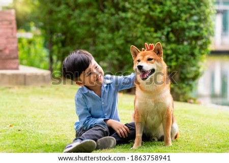 A boy is sitting with a dog by the pool. Asian boy hugging Shiba Inu in a park. Royalty-Free Stock Photo #1863758941