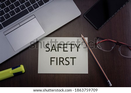 Safety first card. Top view of office table desktop background with laptop, phone, glasses and pencil with card with inscription safety first.  Business concept.