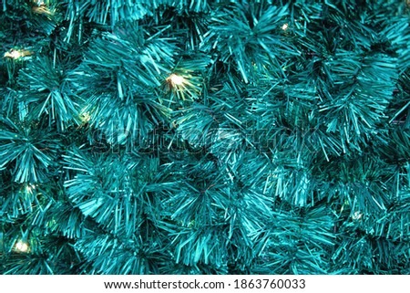 Background of blue artificial Christmas tree with garlands. Tinsel decorations for new year and christmas, copy space