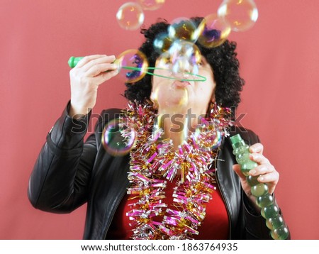 funny picture with woman clown in wig making soap bubbles, children party concept