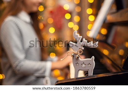Close-up shot of a christmas deer on piano keyboard while little girl playing. Christmas festive mood
