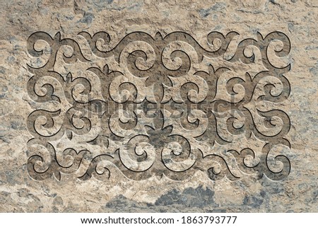 Ornamental print on the stone surface. Vintage ornament on the stone. Embossed drawing. Close-up. Stone texture. Pattern on the stone. Embossed pattern. Wallpaper. Tile