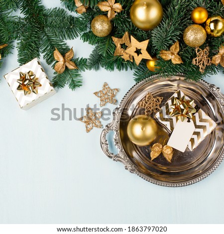 Christmas wreath on blue table, top view. Modern christmas wreath with gold candles, green branches and golden gift boxes on blue background. Winter holiday advent time.